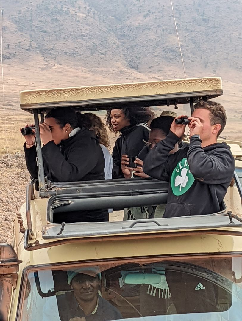 Students looking through binaculars in safari jeep in Tanzania
