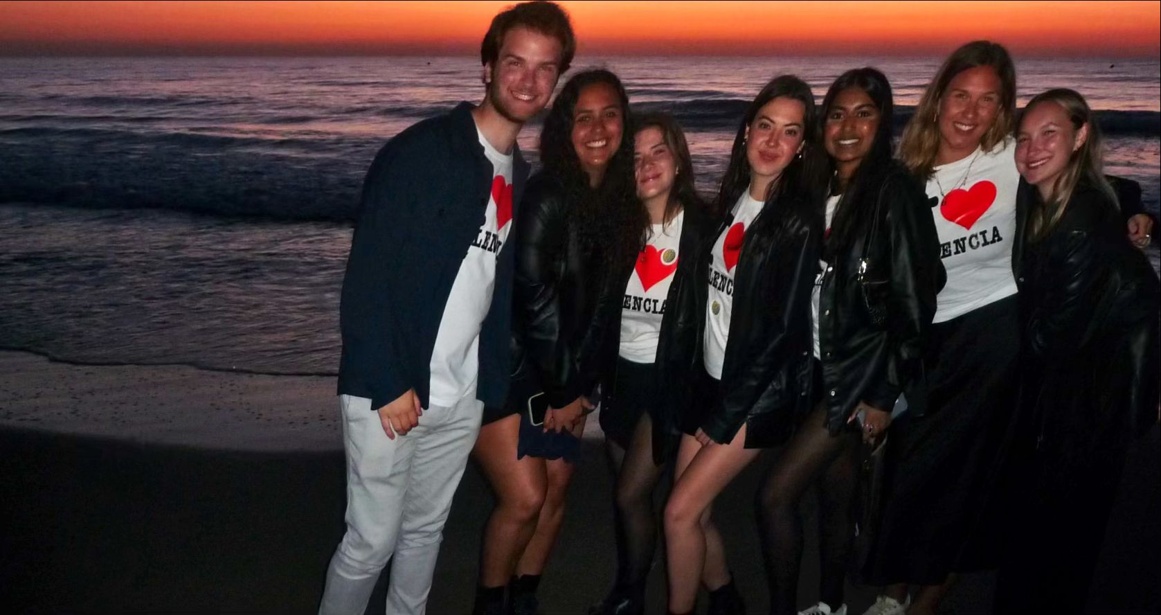 Group of students wearing I Love Valencia shirts on the beach at sunset