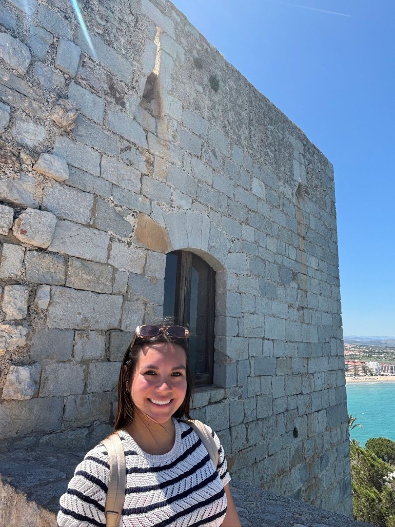 Nicole poses in front of the sea with a black and white striped shirt