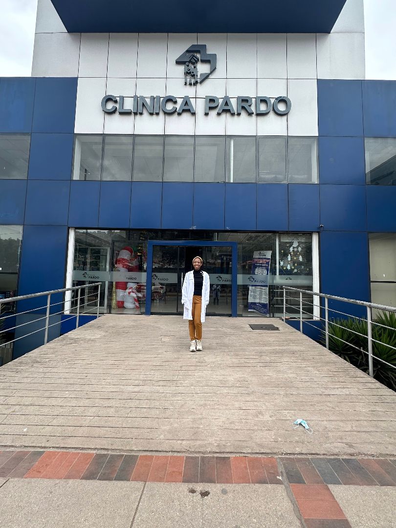Asha wearing a white lab coat standing in front of the Clinica Pardo