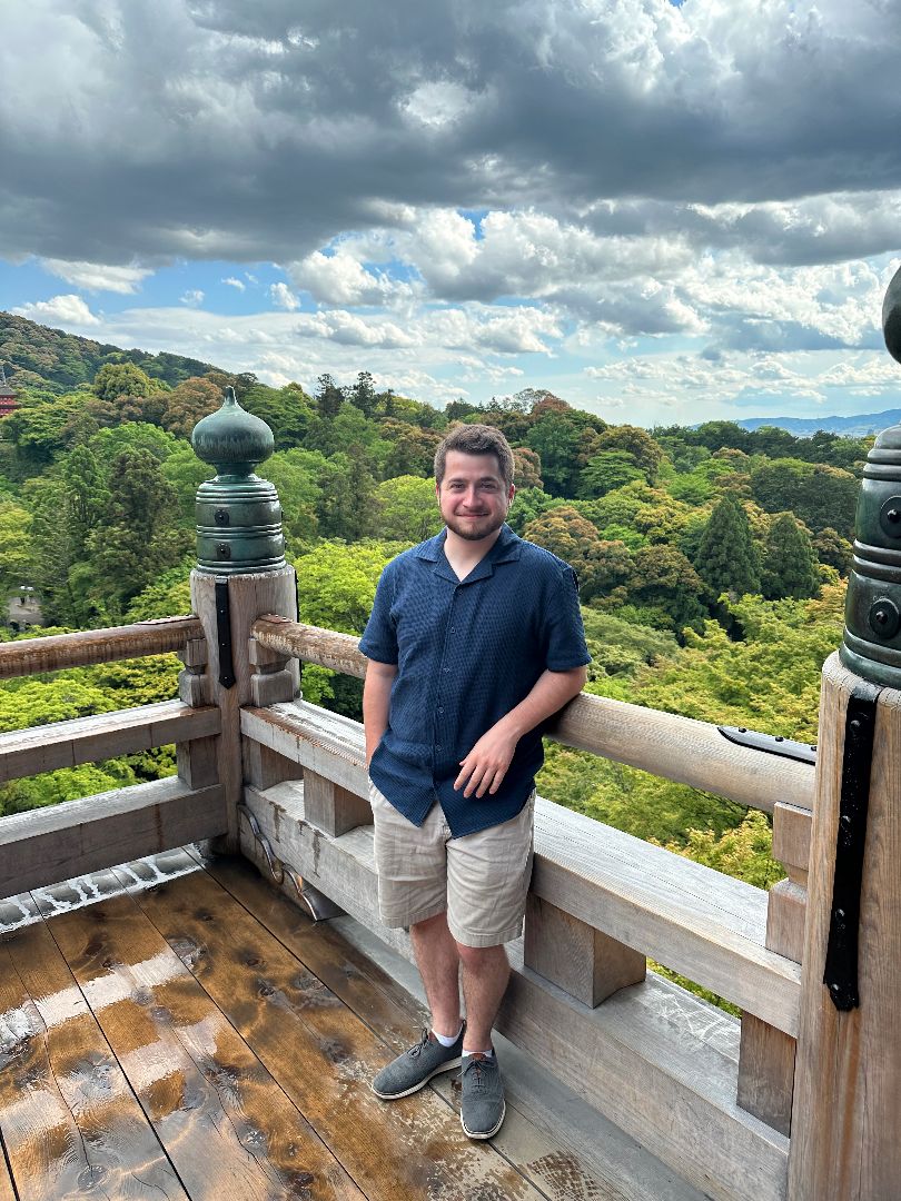 Joseph standing on platform with forested mountains in background in Kyoto