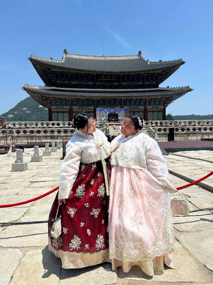 Hanaa and friend wearing traditional Korean dresses in front of a temple