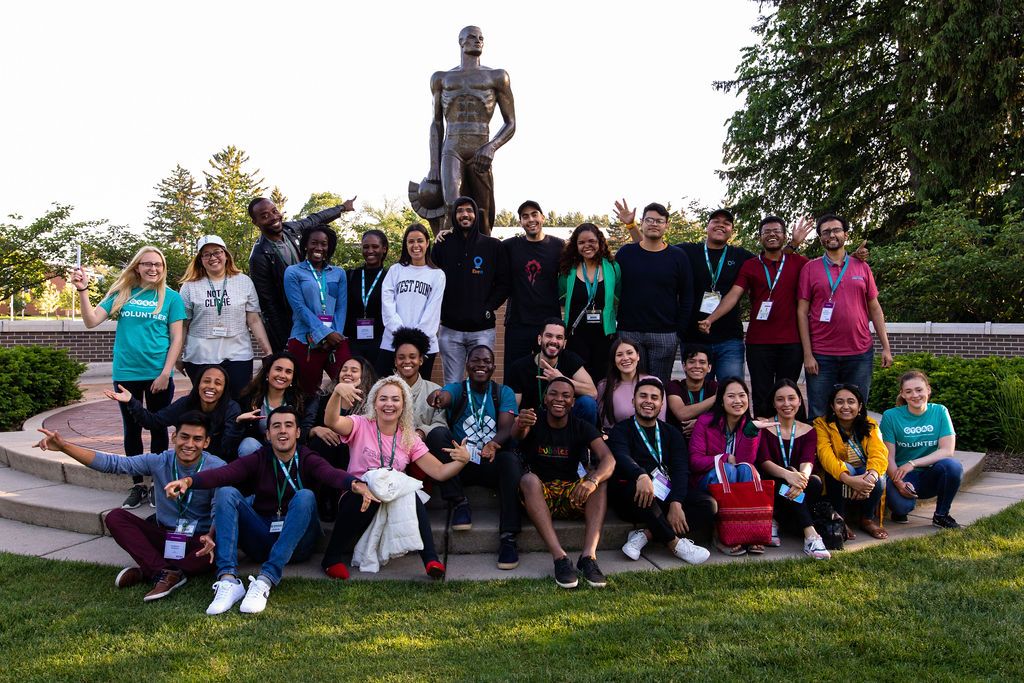 Group of delegates smiling as they pose for a photo at Sparty Statue on the campus of MSU