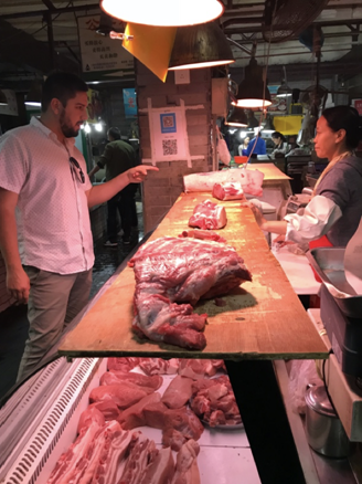 Ortega speaks with a butcher over her counter in a market.