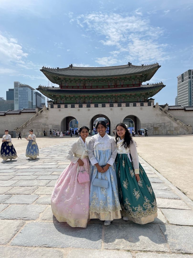 Viji and two friends all dressed in Korean dresses in front of temple