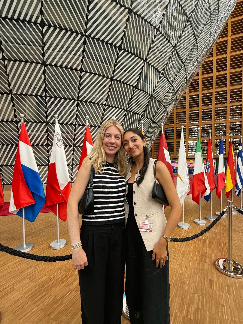 Andrea and friend pose in front of flags at the European Council