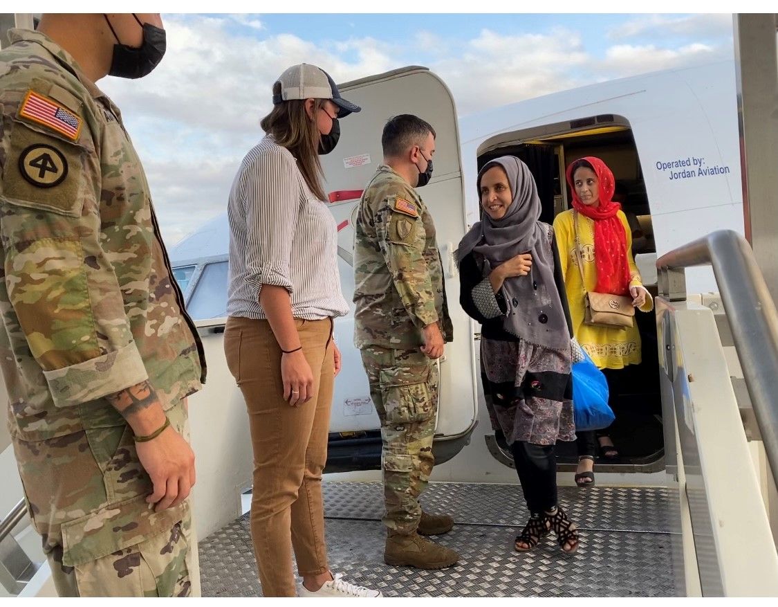 Military officials greet two female Afghan scholars as they exit an airplane