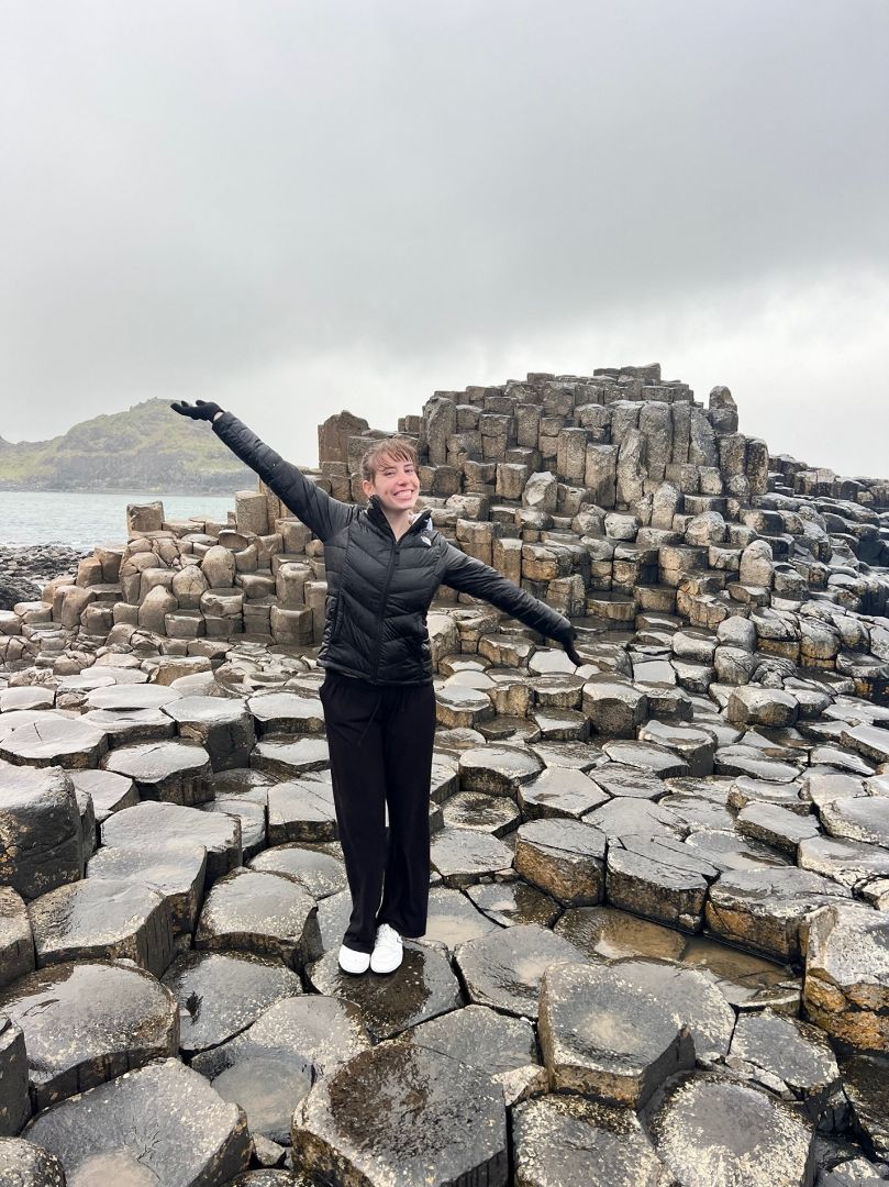 Amanda standing on large rocks near the sea in Ireland