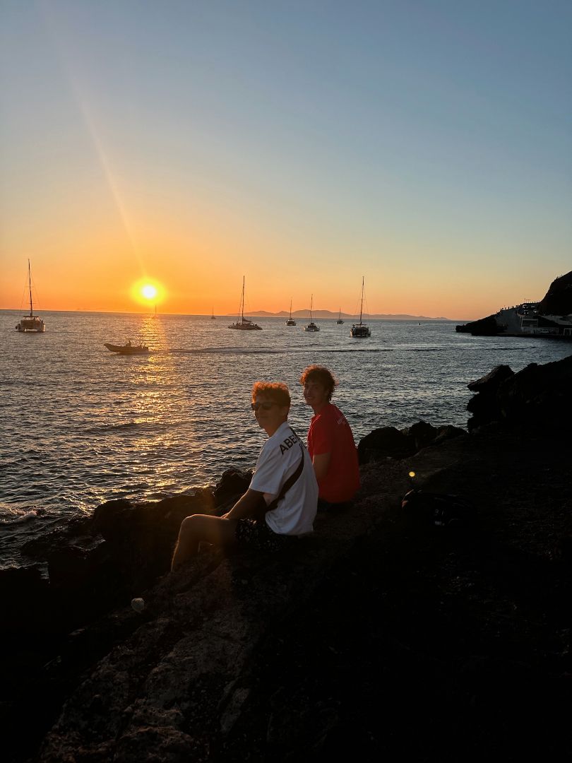 Brady sitting by the sea during sunset with a friend