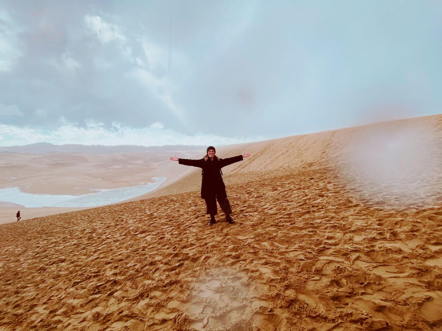 Ryan with his arms spread wide while standing in the Sand Dunes of Tottori city