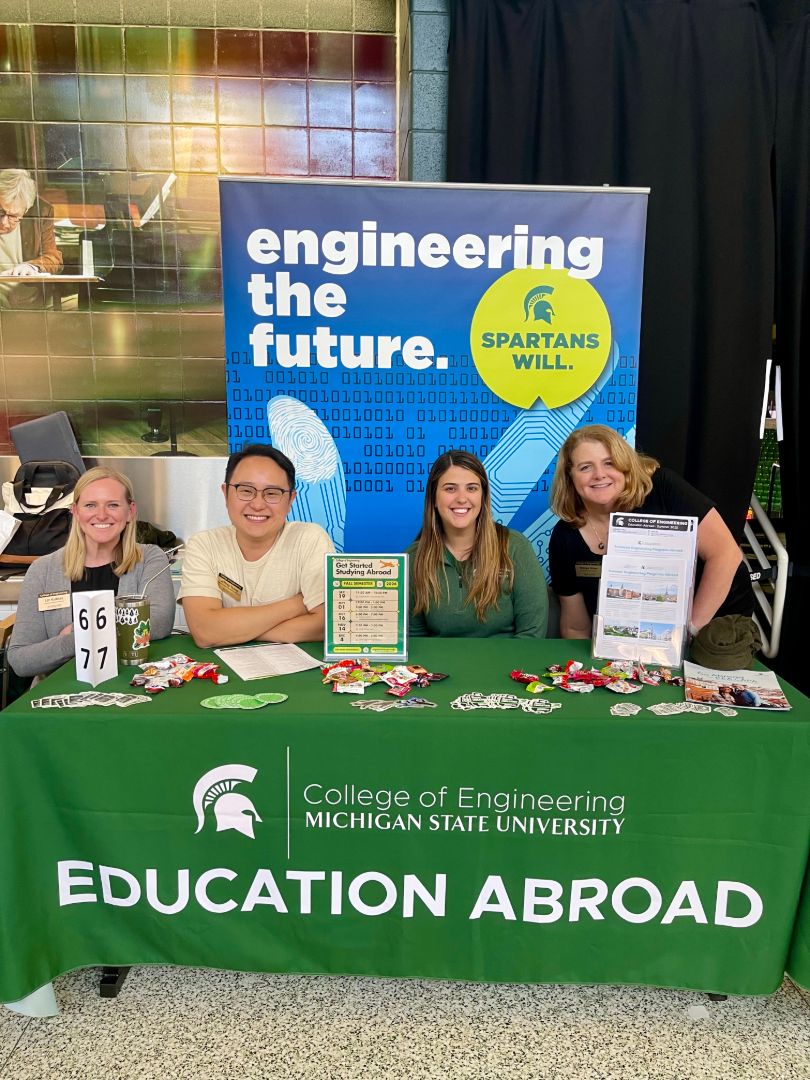 Members of the engineering advising team sitting behind a table with a banner saying "Engineering the future"