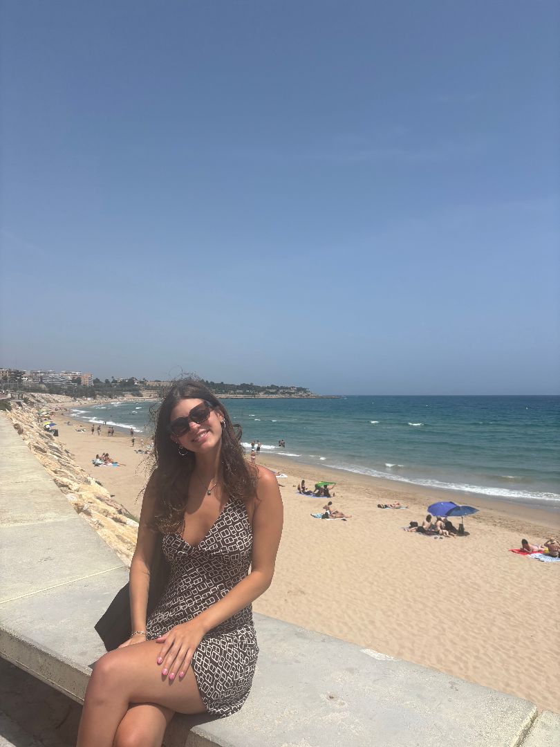 Victoria sitting on a stone wall by the beach
