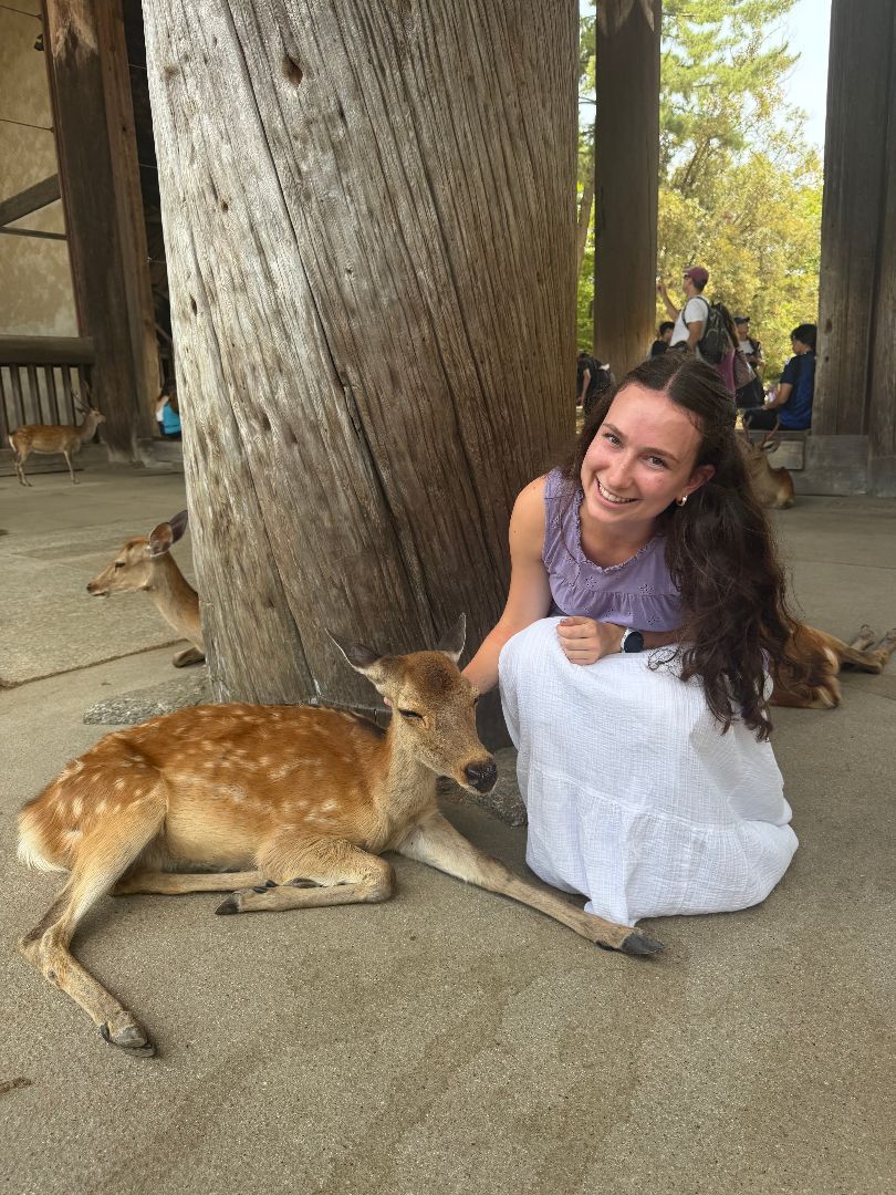 Anika kneeling down next to a deer in Nara Park in Japan
