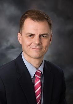 Headshot of man in a suit smiling at the camera.