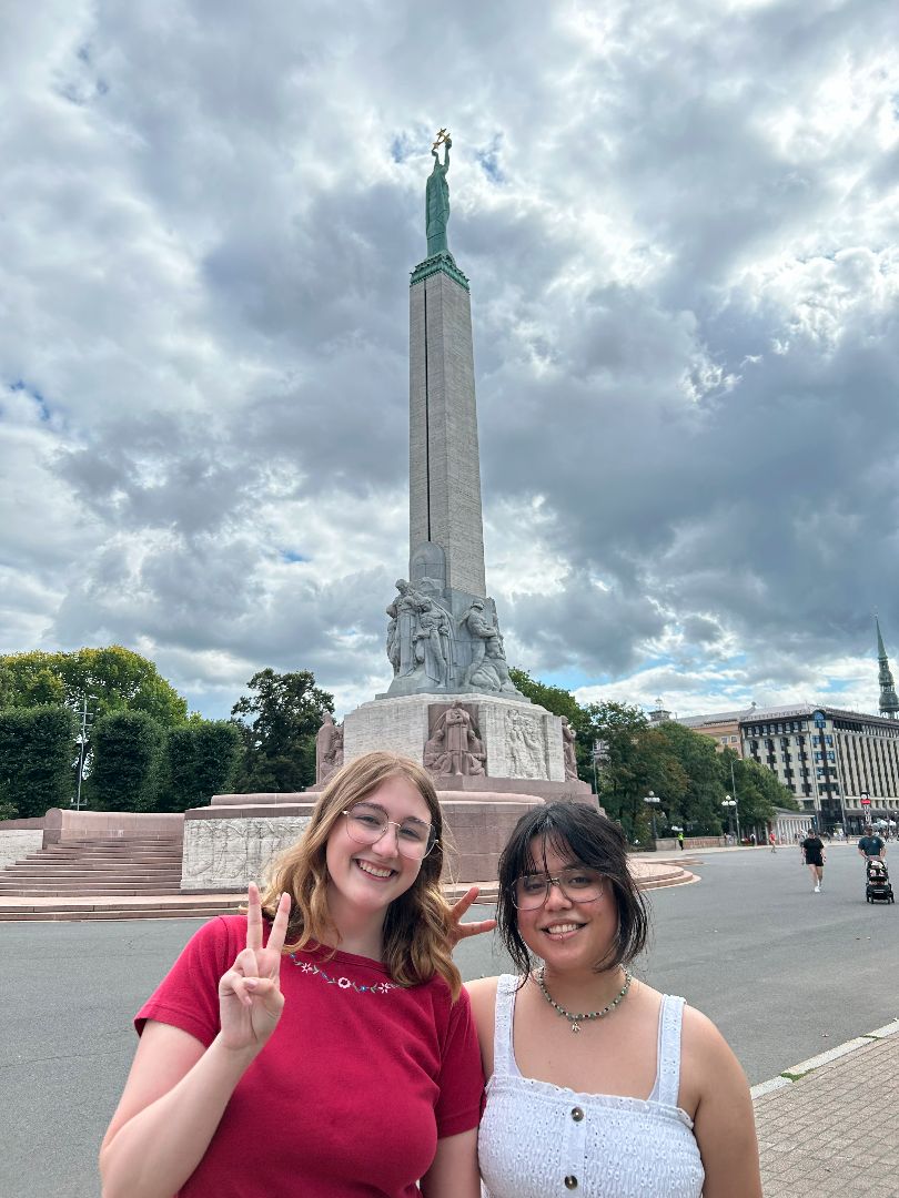 Chelsea and friend hold up peace signs in front on the Freedom Monument in Latvia