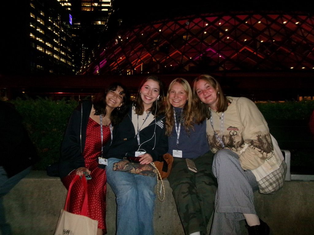 Evelyn and friends pose on a cement wall at night in downtown Toronto