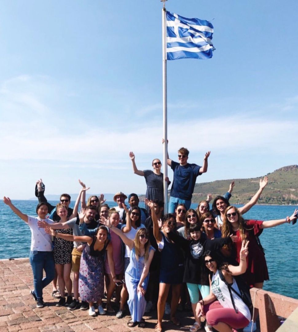Group of student sitting by Greek flag in Greece