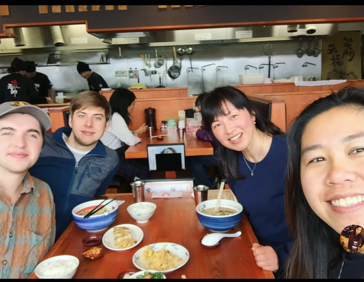 4 smiling people sitting at a table at a ramen shop
