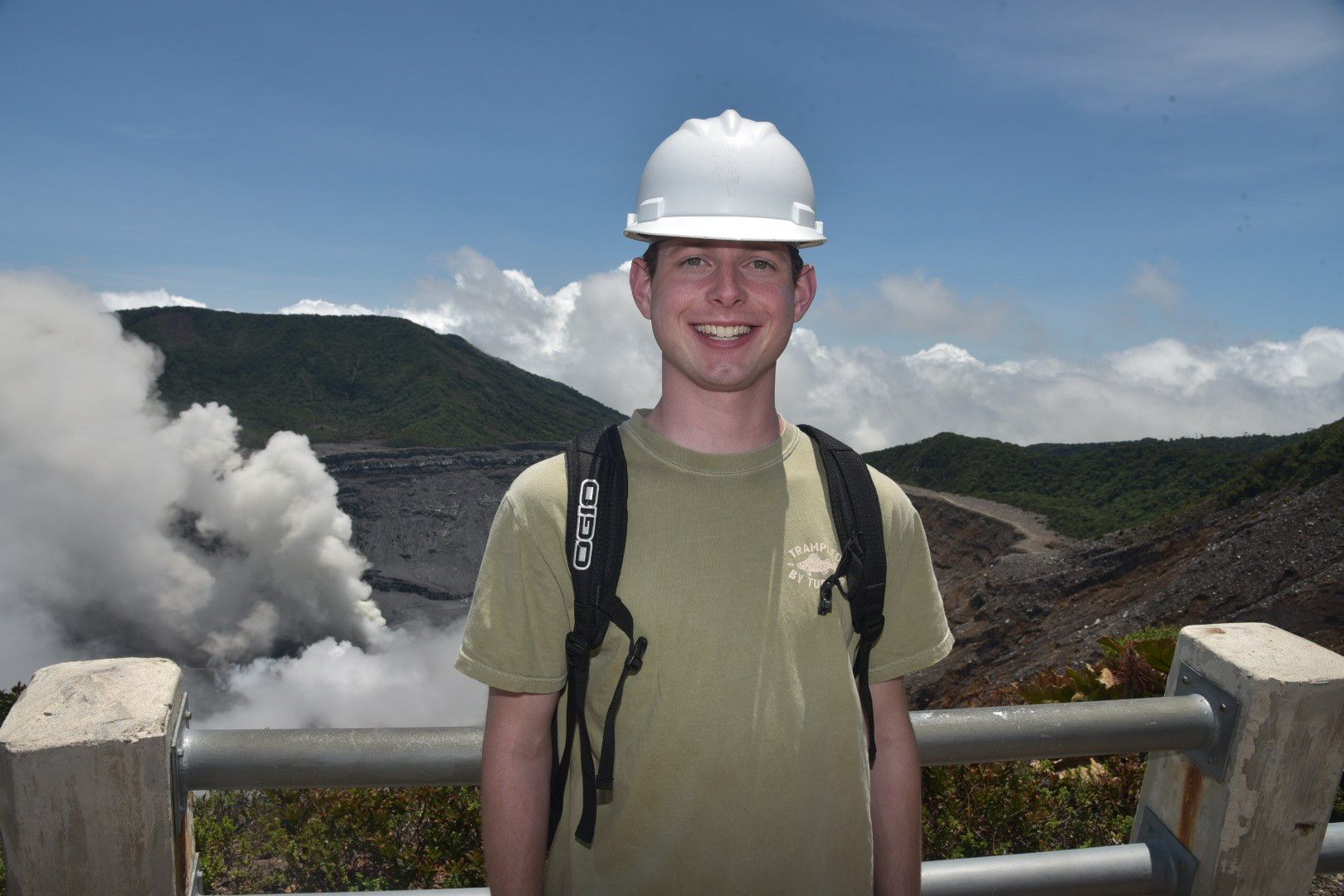 Paddy in front of a volcano wearing a white hard hat