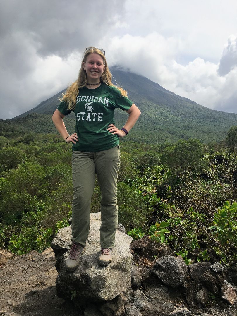 Oliva standing in front of the Arenal Volcano with MSU shirt on in Costa Rica