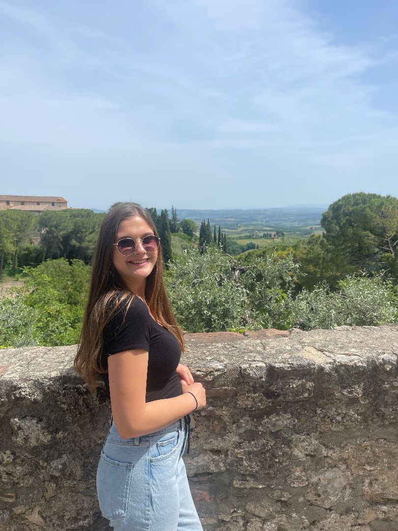 Kaylee standing next to old stone wall in Italy