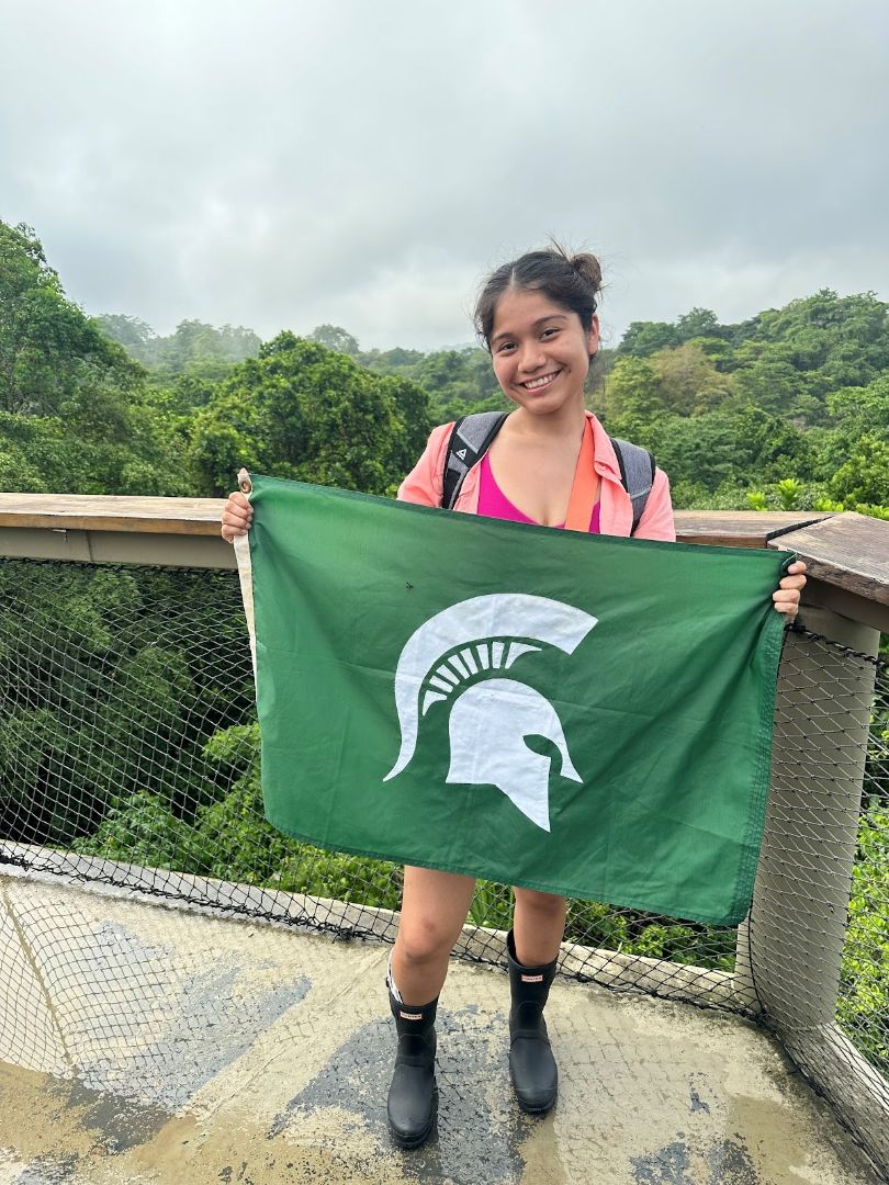 Michelle holding a Spartan flag in the rainforest of Panama