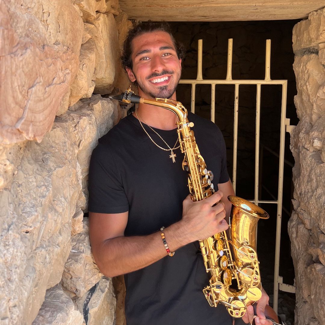 Luke holding saxophone in stone doorway in Israel