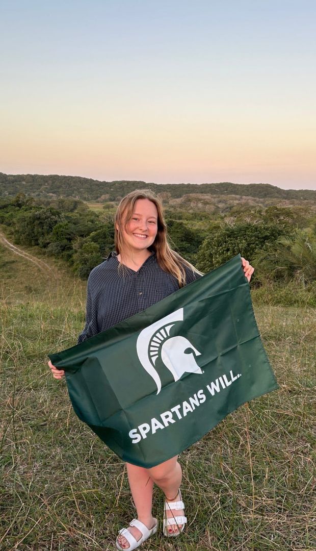 Lyric holding a Spartans Will flag on top of a mountain 