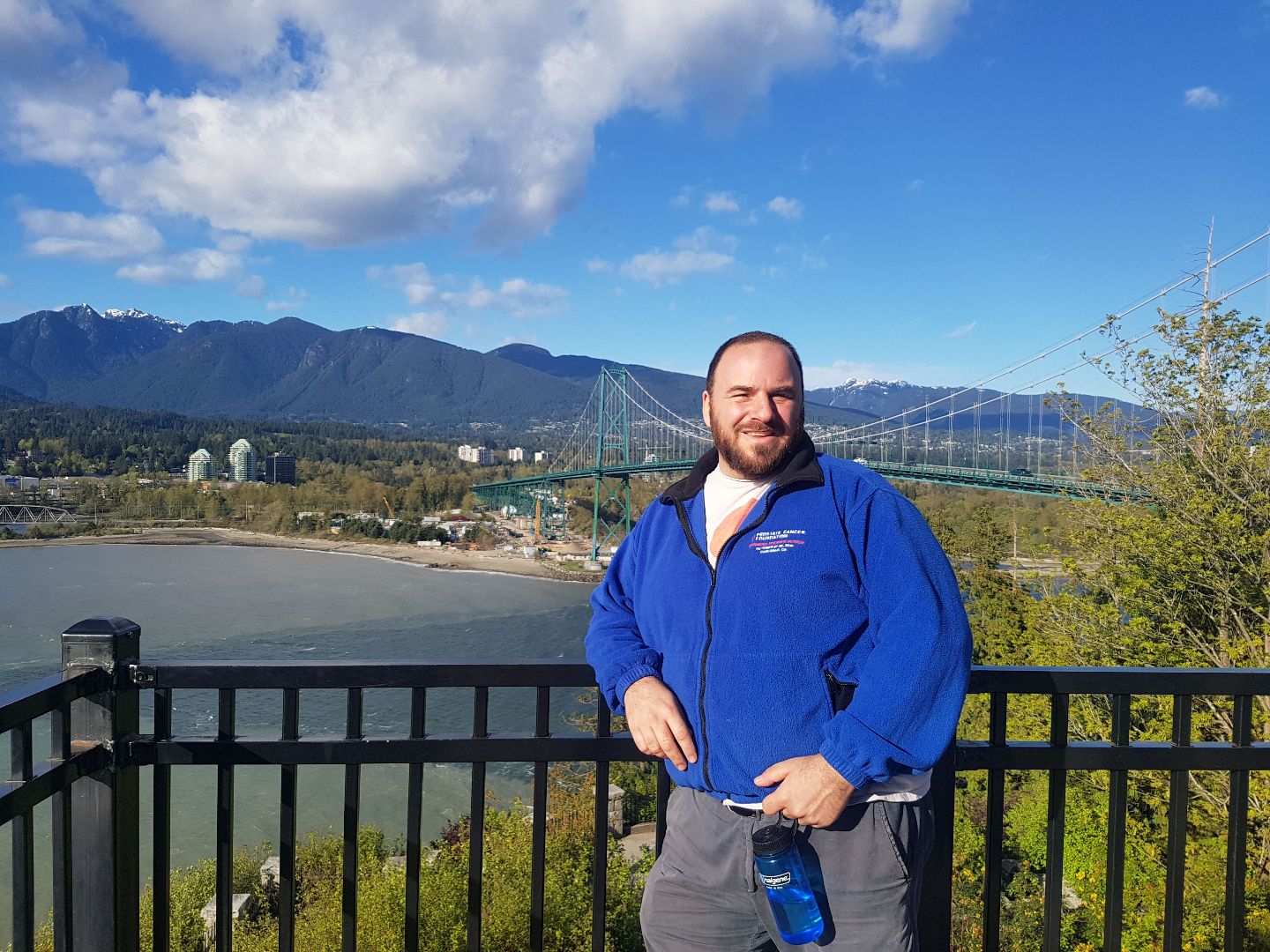 Jon standing in front of a fence with river and suspension bridge in the background