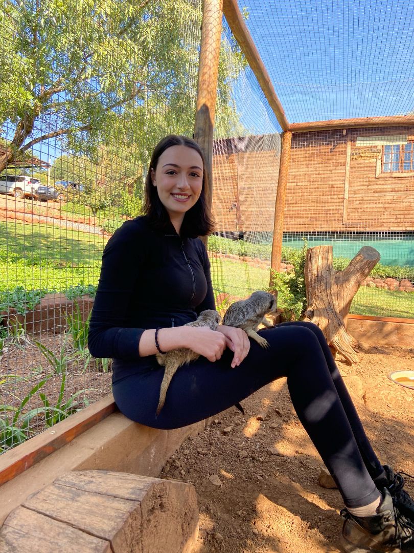 Maria holding two Meerkats in her lap in South Africa