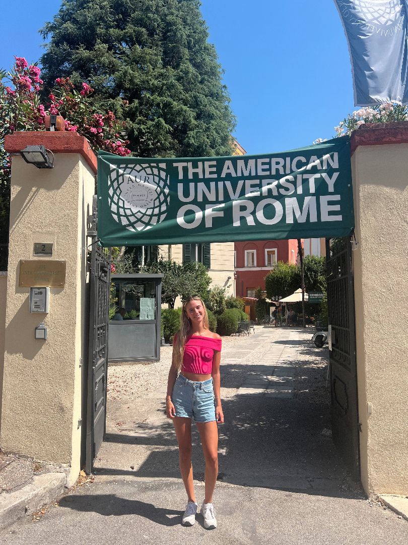 Gianna standing in front of a banner that reads The American University of Rome