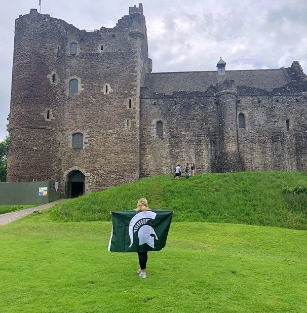 Summer holding Spartan flag in front of Scottish castle