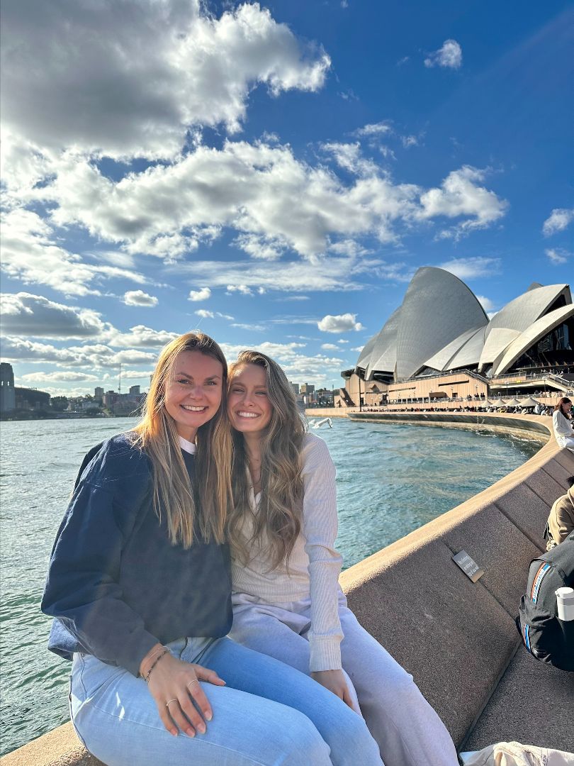 Taylor and friend sitting on a wall in front of the Sydney Opera House