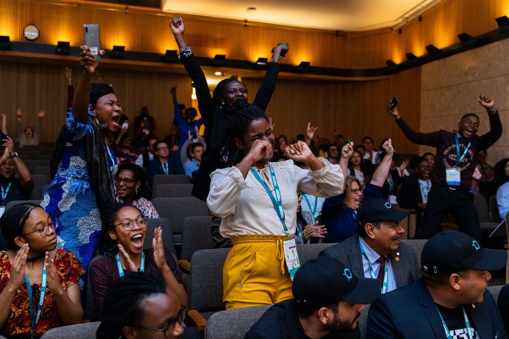 Group of people in the auditorium of the Kellogg Center cheering, clapping and smiling at GYAS competition.