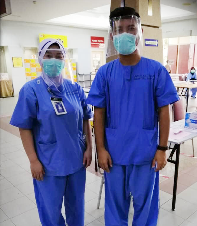 Ghazali stands next to a colleague wearing his 3D printed masks.
