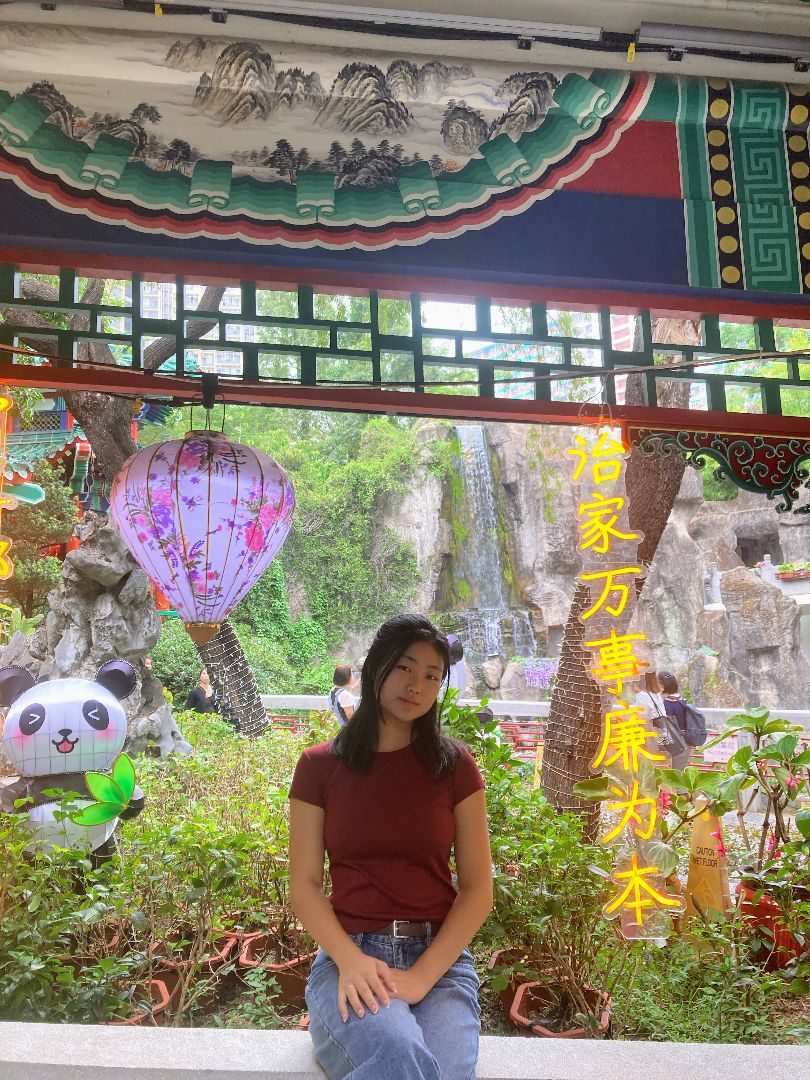 Katrina sitting in a garden with a panda figure in the background and a purple hot air balloon hanging above her