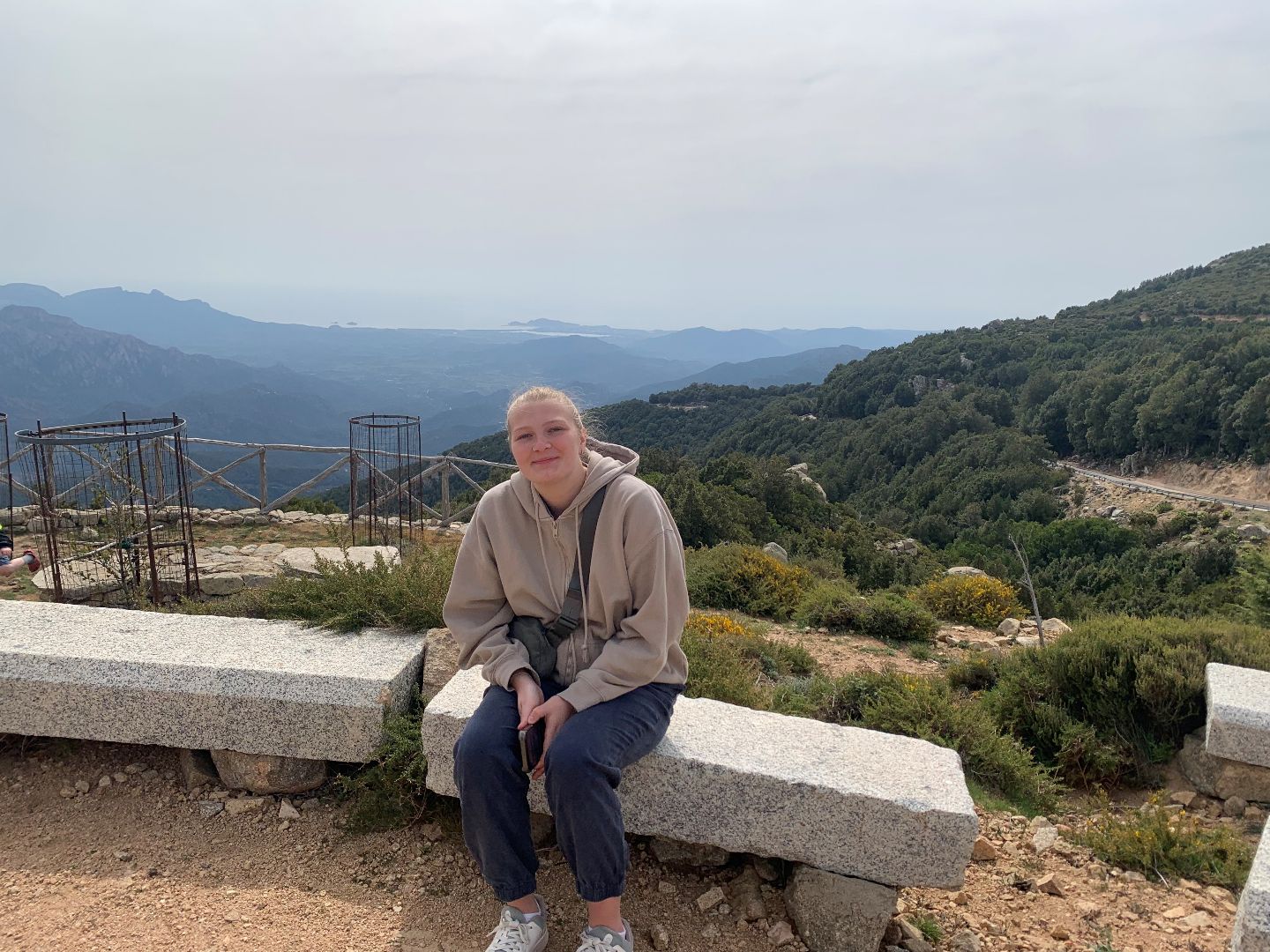 Olivia sitting on a stone bench on top of a mountain in Italy