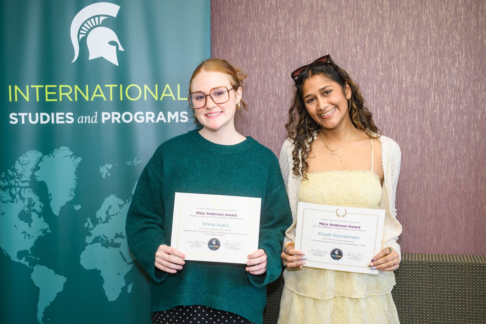 Khushi and Emma smiling and holding their award certificates