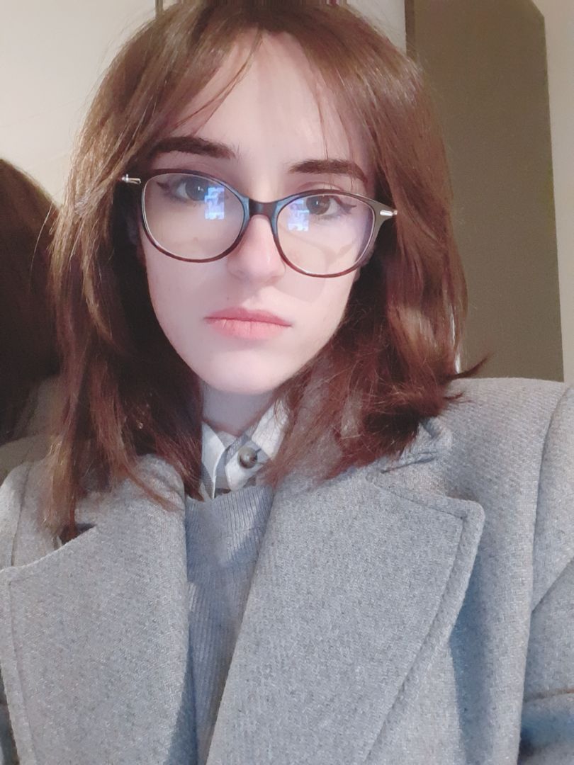 A young woman with dark hair and glasses poses for the camera