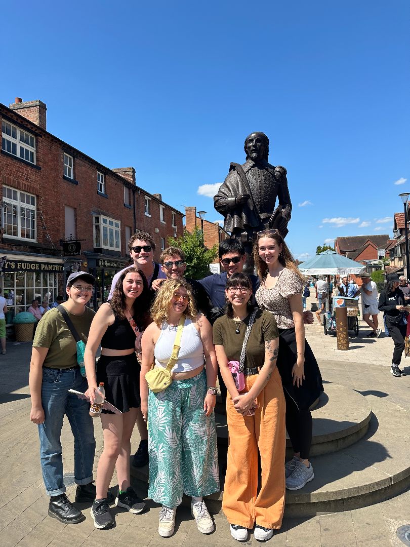 Ray and friends posing in front of a statue of Shakespeare