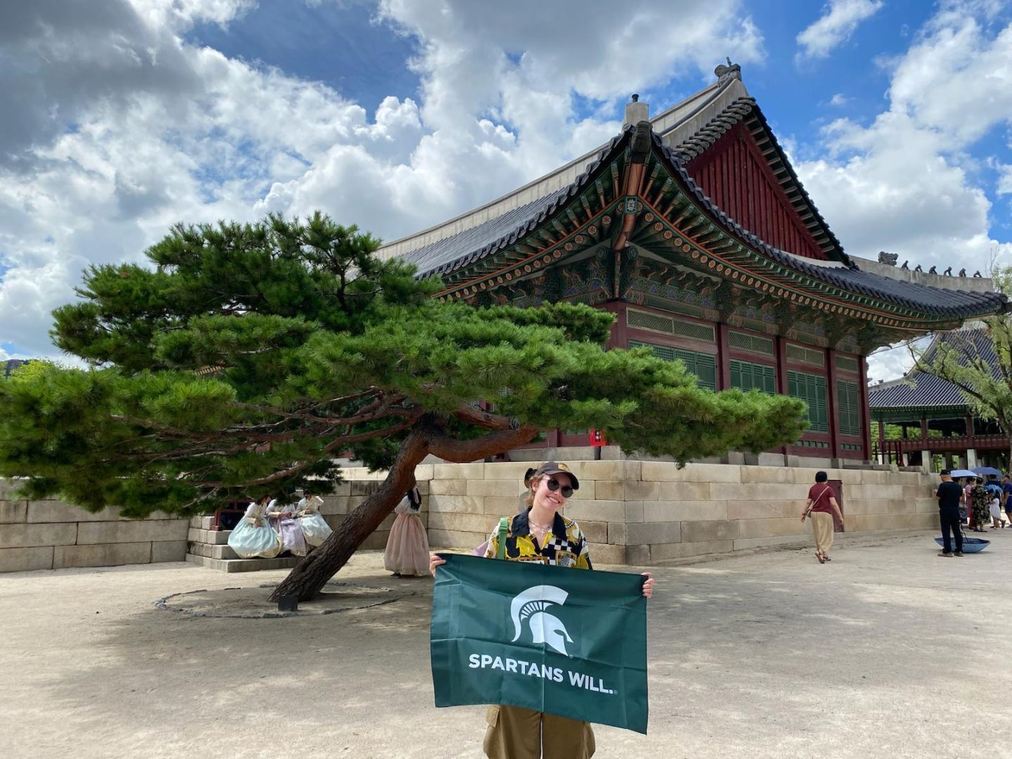 Keara wearing sunglasses and holding a Spartan flag in front of an ornate temple
