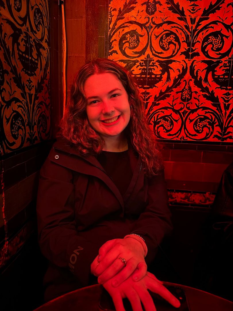 Elizabeth sitting in a dark room lit with red lights