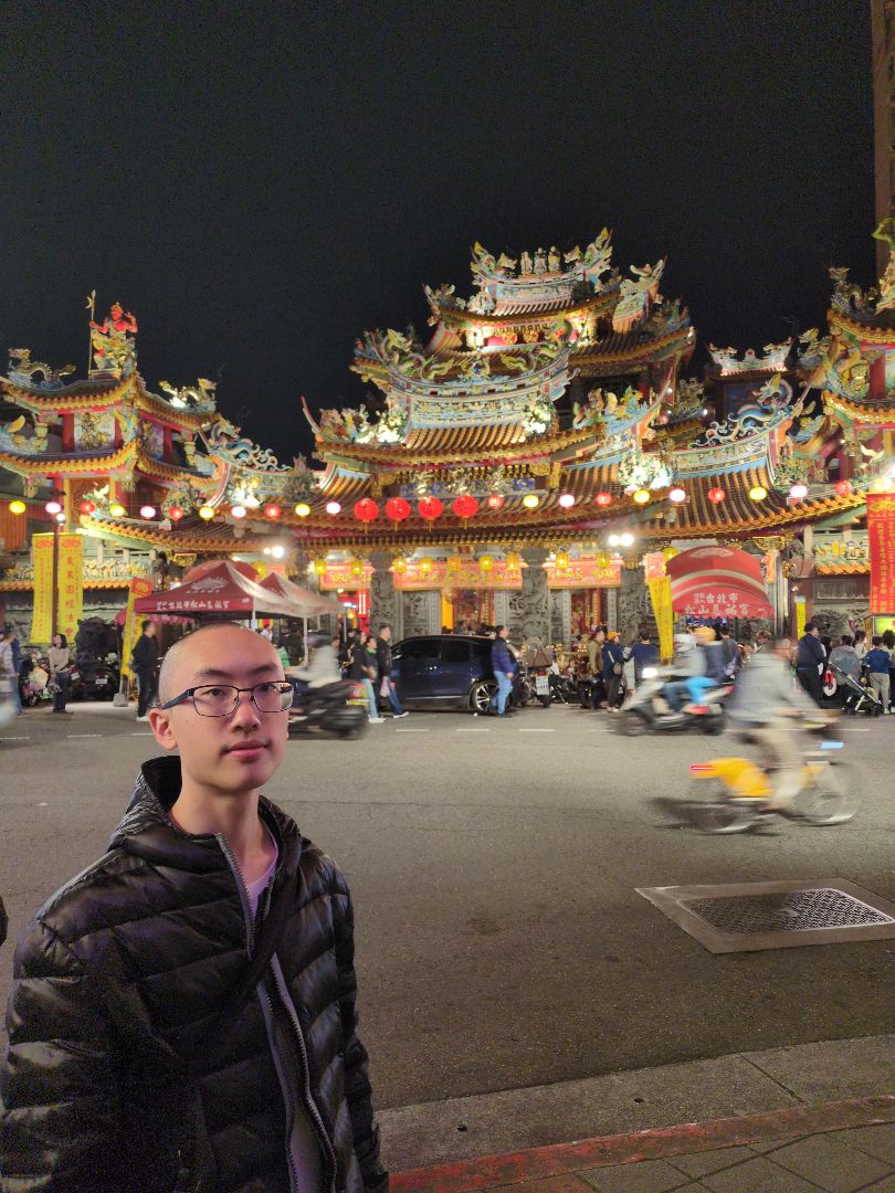 Shane taking a selfie at night in front of an ornate building in Taiwan