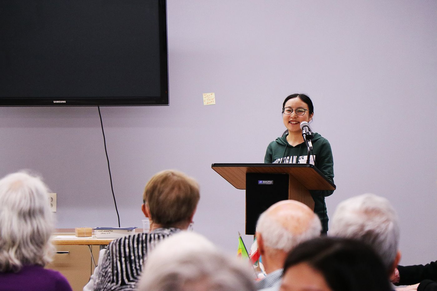 Female scholarship recipient standing at podium to accept recognition 