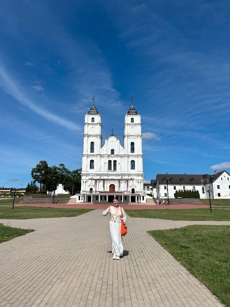 Chelsea standing in front of a historic white building in Latvia