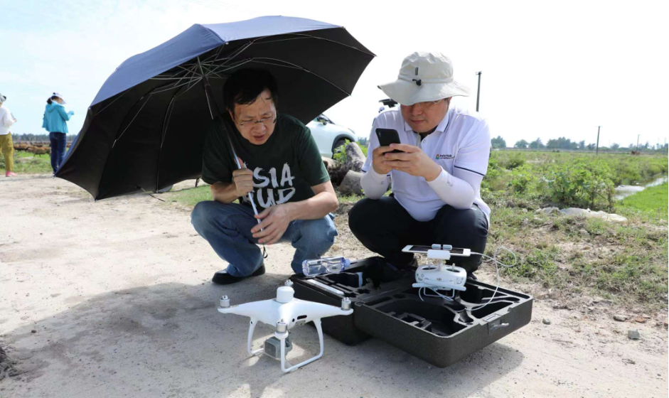 Two scientists kneel over a drone during field site visit.