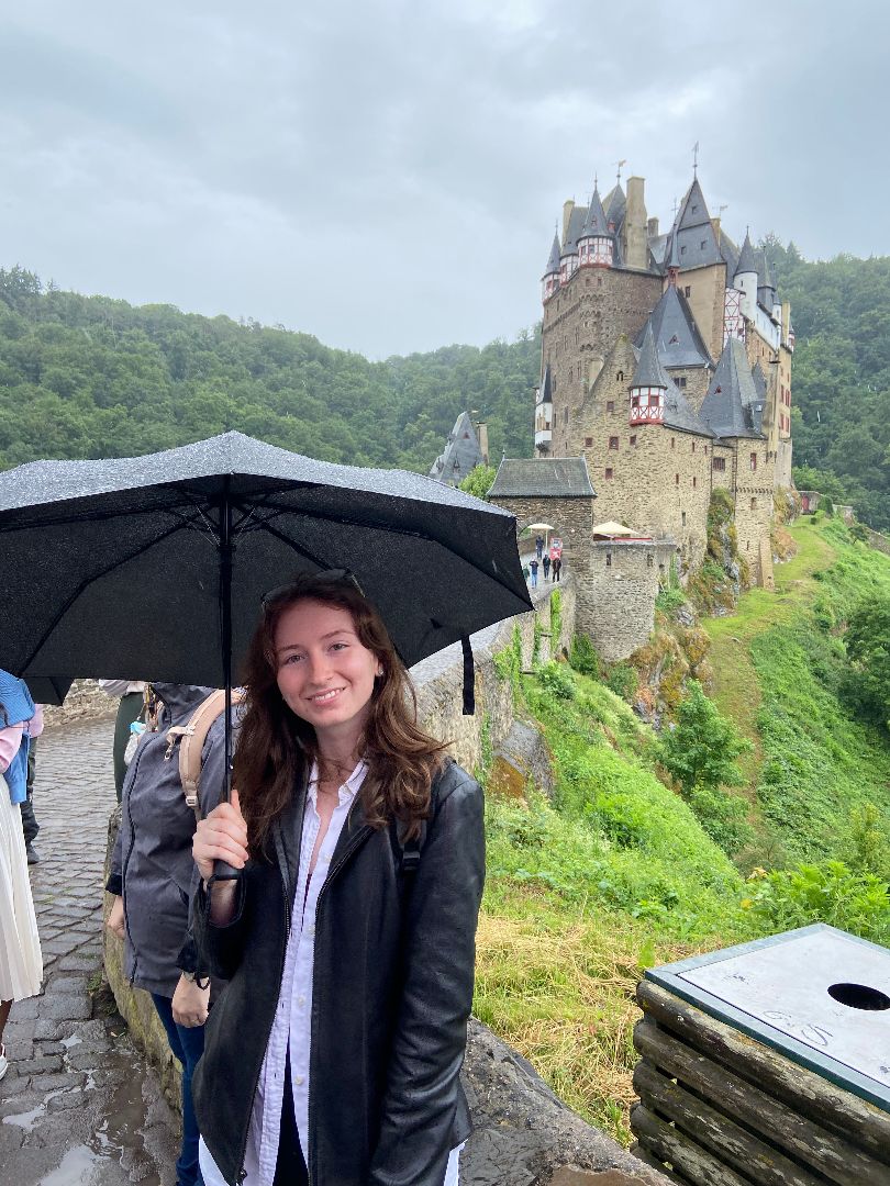 Ellie standing with an umbrella in front of a castle in Germany
