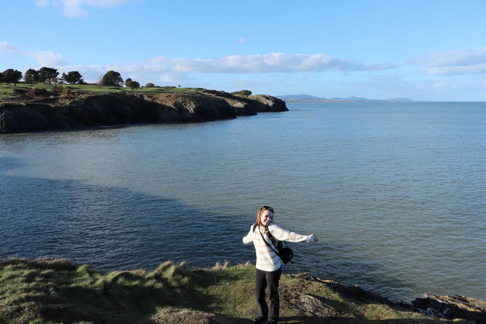 Lilly standing with her arms open on the coast of Ireland