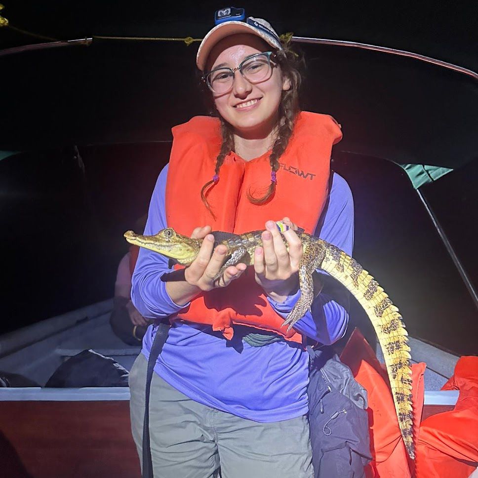 Marieke wearing an orange life vest holding a small caiman in Panama