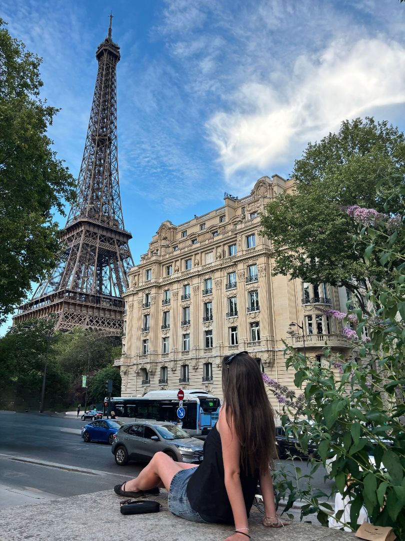 Jovana sitting on a cement wall looking at the Eiffel Tower in Paris